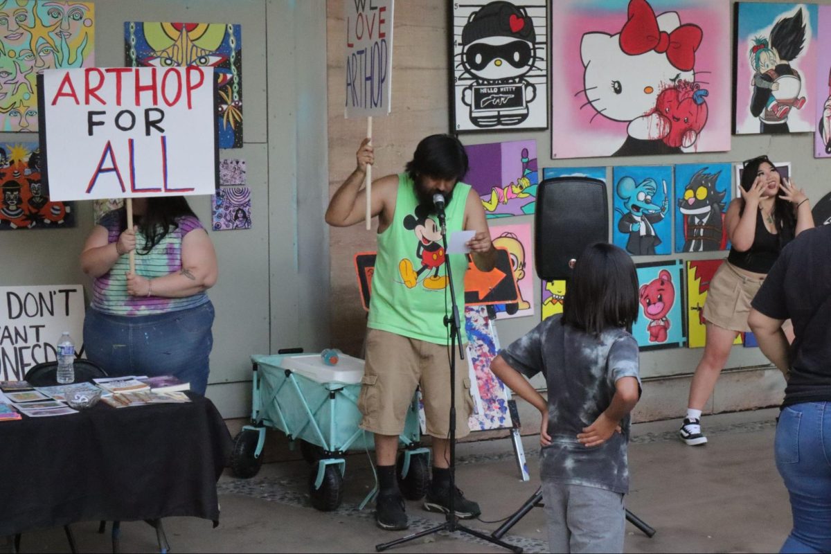 A crowd watches Rodriguez speak up for the reestablishment of traditional ArtHop as Rocha (left) holds a picket sign on Sept. 5.