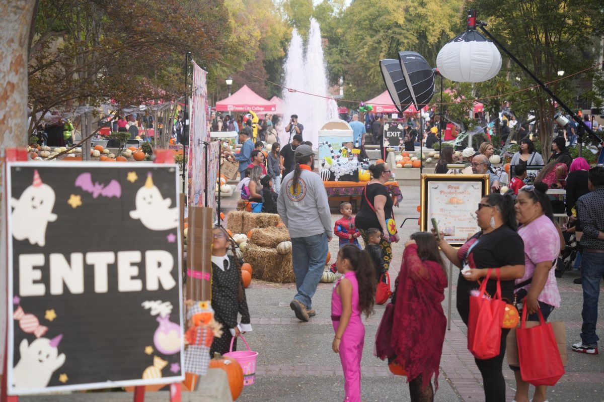 Child dressed up as Mario frowns while sitting at a large fountain dyed red during Fresno City Colleges Fall Carnival at University Mall, Oct, 25. 