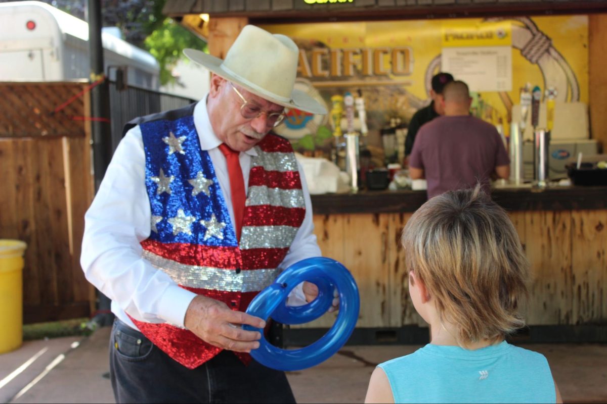 Dennis Forel makes a snake balloon animal for a child at The Big Fresno Fair on Oct. 10, 2024. 