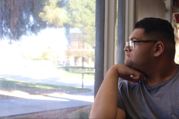 Reporter Matthew Karim poses and looks out of the window into the Fresno City College campus on Oct. 23. 