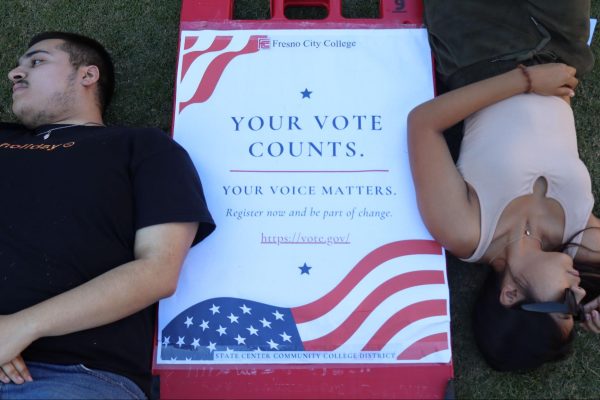 (Left to right) Fabio Saravia and Brisa Serna face away from a sign encouraging students to vote on Oct. 23. 