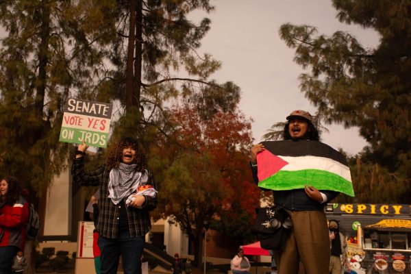 Student protestors chanting with one protestor holding up a sign in reference to the series of JRDs motions on Nov. 19.